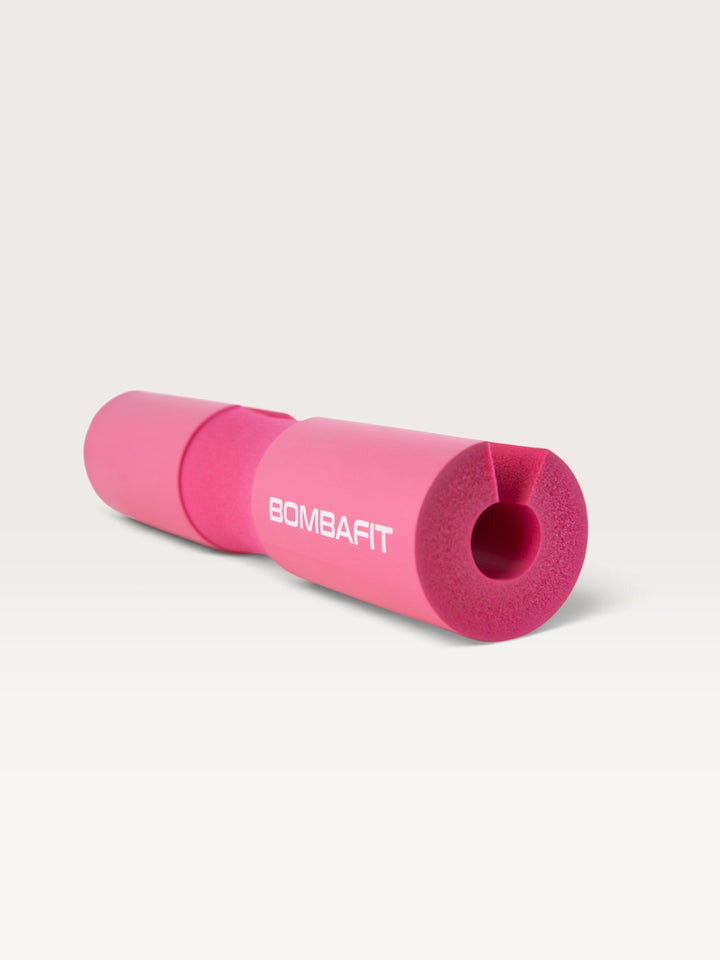 Cuscinetto imbottito per bilanciere Bombafit di colore fucsia, ideale per proteggere il collo durante gli squat.