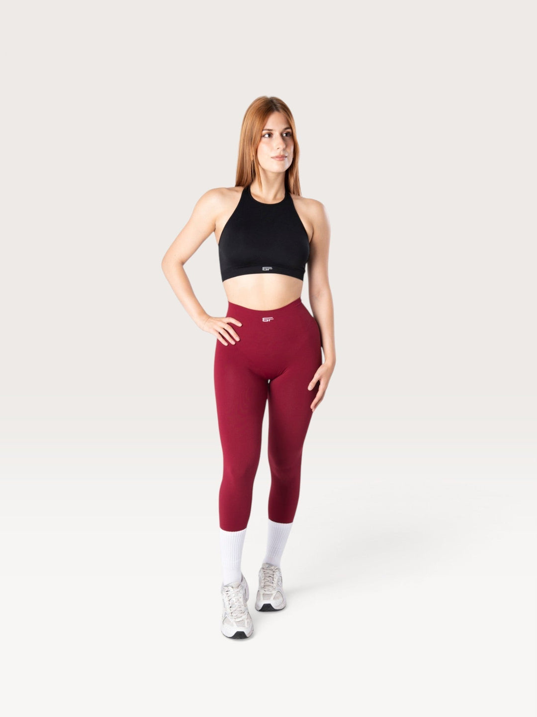 Modella indossa leggings Bombafit Arya Seamless color borgogna a vita alta con effetto push-up e top sportivo nero