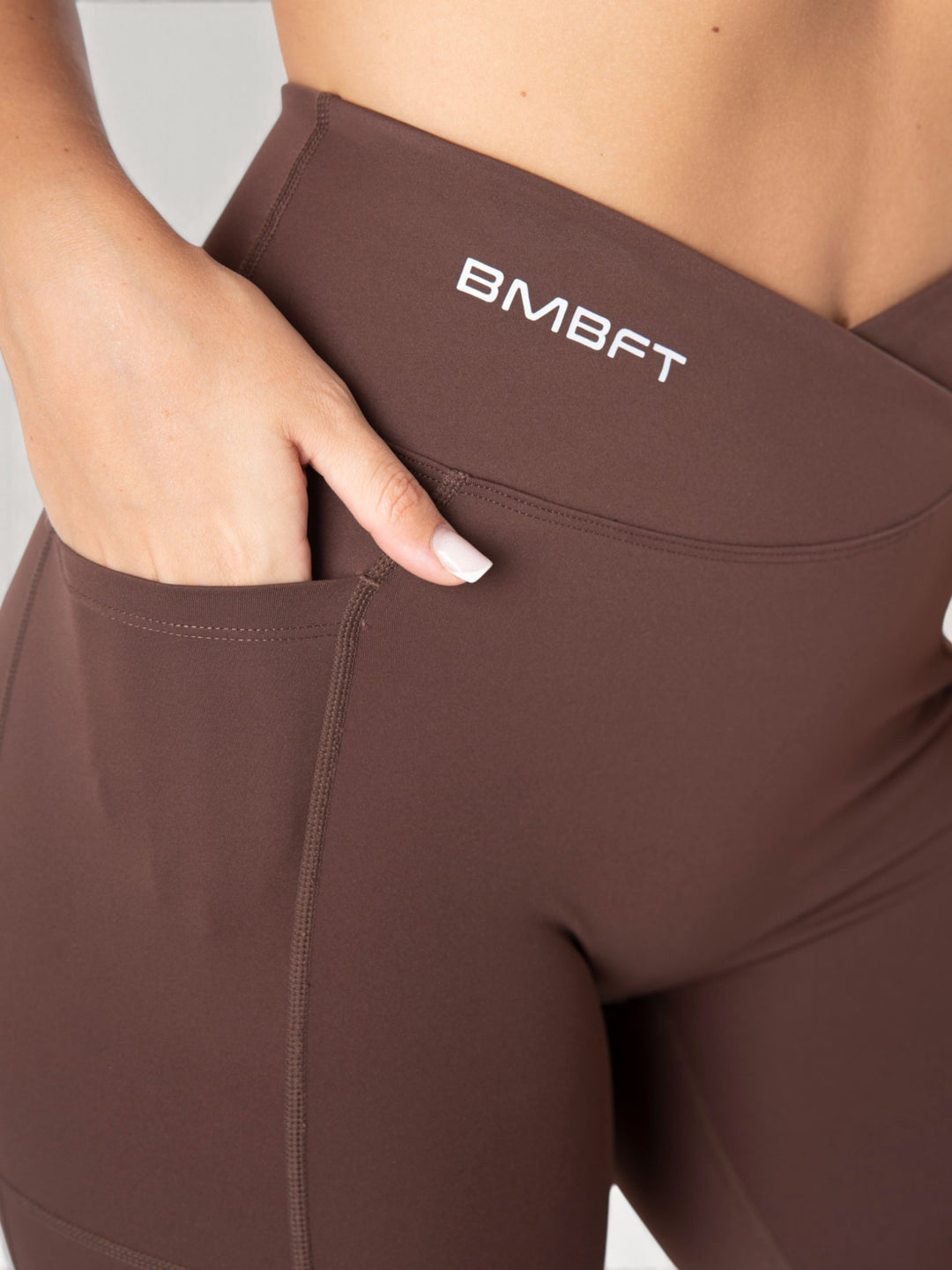 Leggings Bombafit marroni a vita alta con dettaglio incrociato, tasca laterale e logo BMBFT stampato
