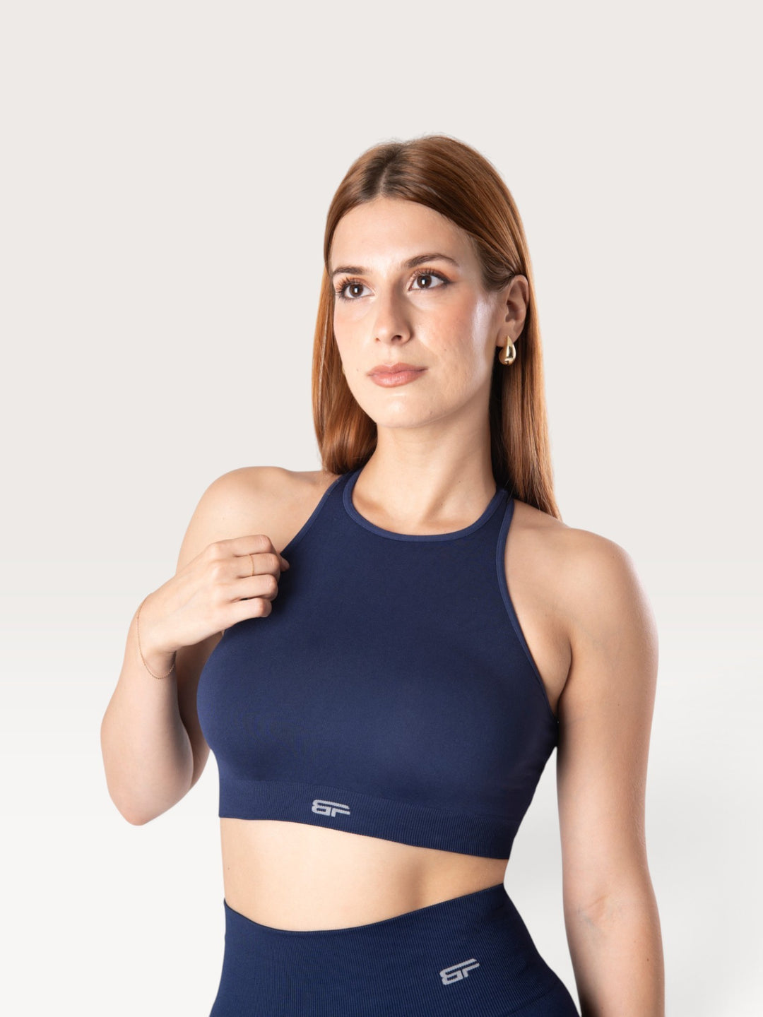 Modella indossa il top sportivo Bombafit Go Seamless blu notte con design a vogatore e logo riflettente