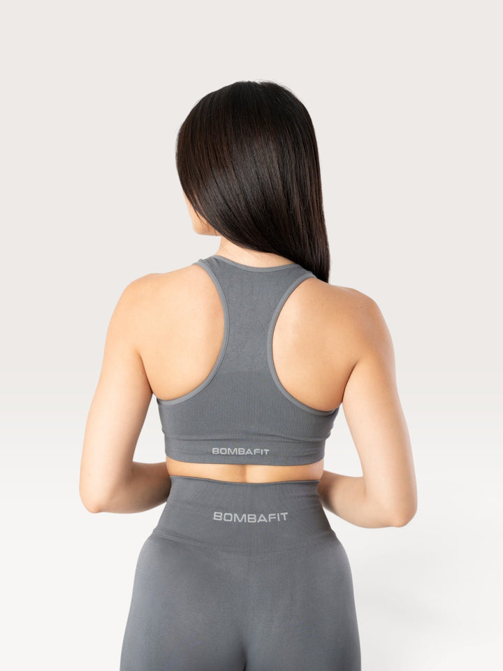 Vista posteriore di una modella che indossa il top sportivo Bombafit Active Seamless color grafite con taglio racerback